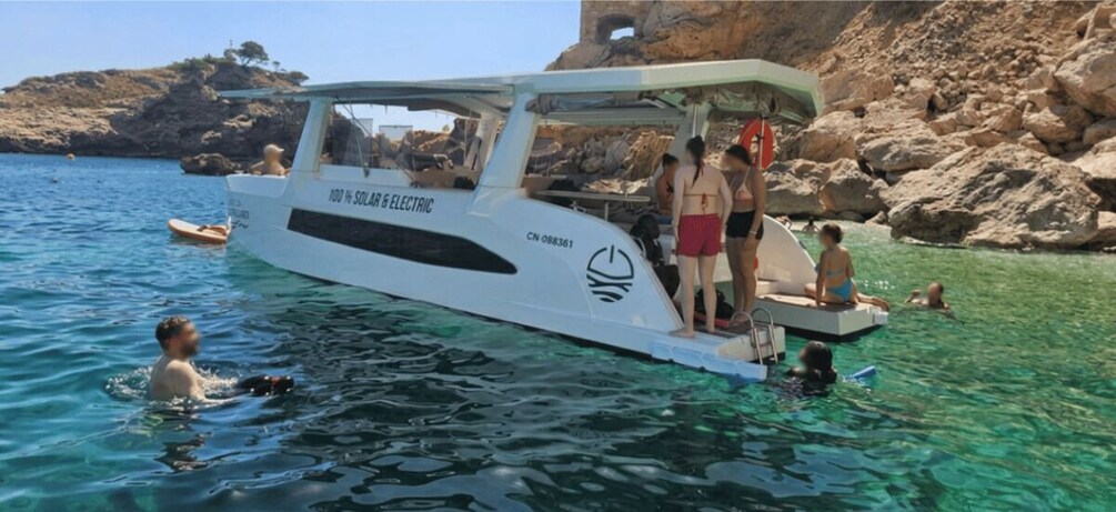 A boat with people on it and others swimming in the water. 2