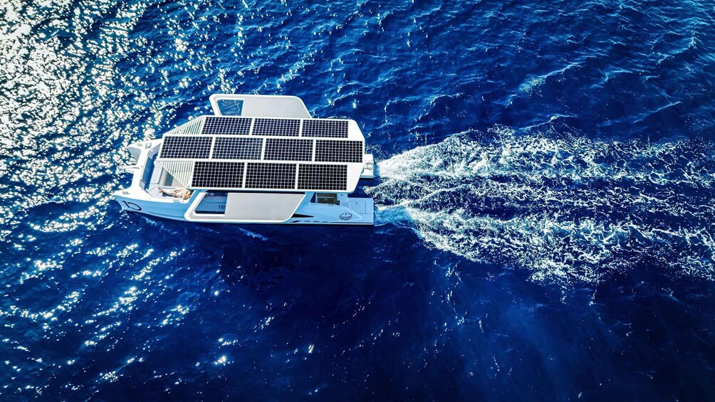 A white boat with solar panels on the deck, sailing on a blue ocean. 4
