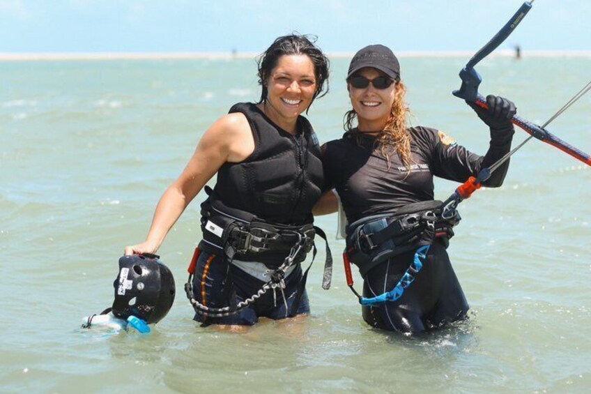Two people in water with life vests and a kiteboard. 2