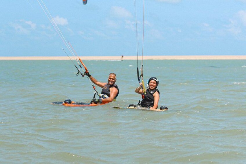 Two people windsurfing on calm water with a clear sky and a distant shoreline. 4