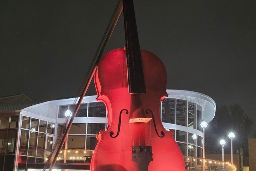 A large red violin sculpture in front of a modern building with glass windows. 5