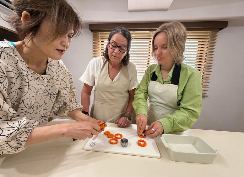 Three people preparing food, with a cutting board and kitchen utensils on a table. 3