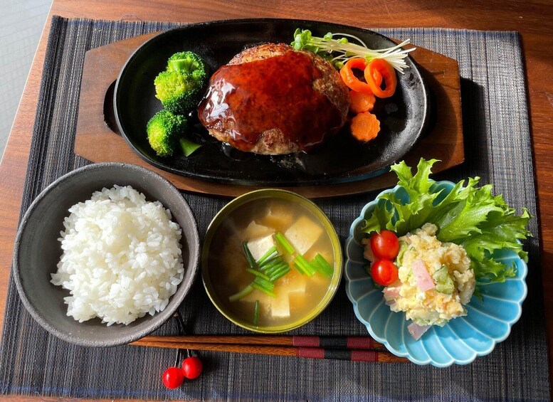 A meal with rice, soup, and salad on a woven placemat. 4