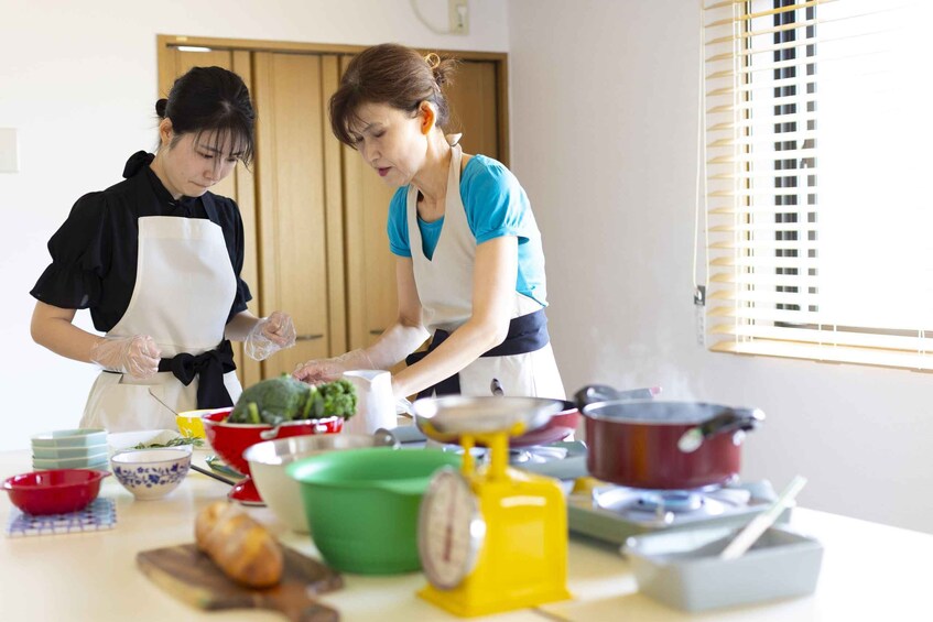 Two people cooking with various kitchen utensils and ingredients on a table. 2