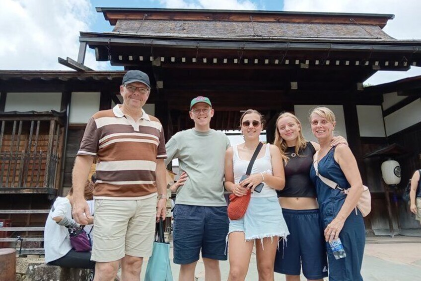 A group of people standing in front of a traditional wooden building with a tiled roof. 3