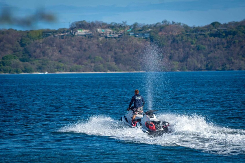 Una persona conduciendo un jet ski sobre el agua, con una costa boscosa al fondo. 5