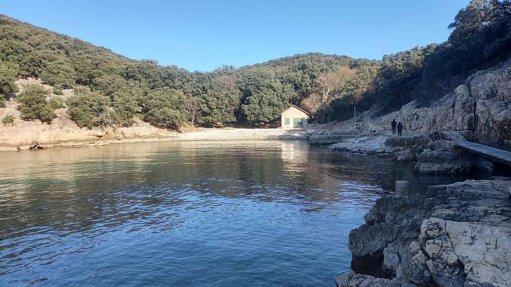 A calm river with a small house on the bank, surrounded by forested hills. 4