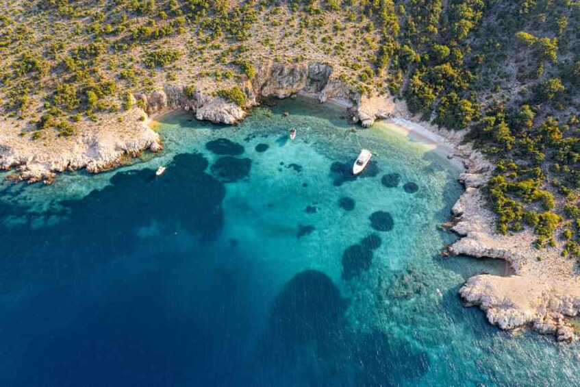 A coastal landscape with clear turquoise waters, rocky outcrops, and sparse vegetation. 1