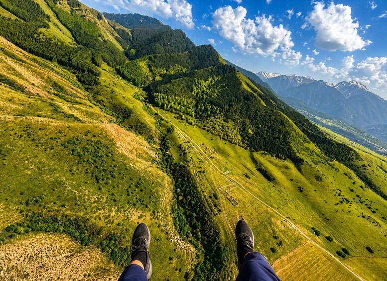 A person standing on a grassy hillside with a mountain range in the background. 5