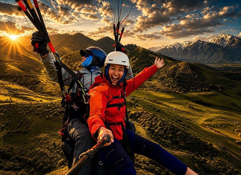 Two people paragliding over a mountainous landscape with the sun setting in the background. 4