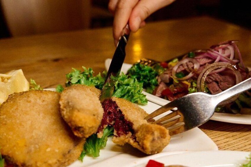 A plate with breaded cutlets, a salad, and a lemon wedge. 1