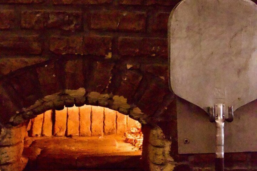 A brick oven with a pizza peel in front. 5
