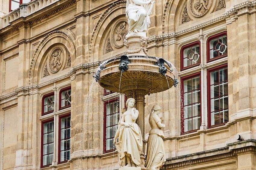 A historic building facade with ornate sculptures and a large fountain. 5