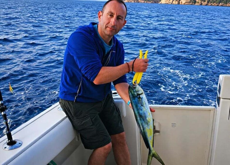 A person holding a fish on a boat in the ocean. 4
