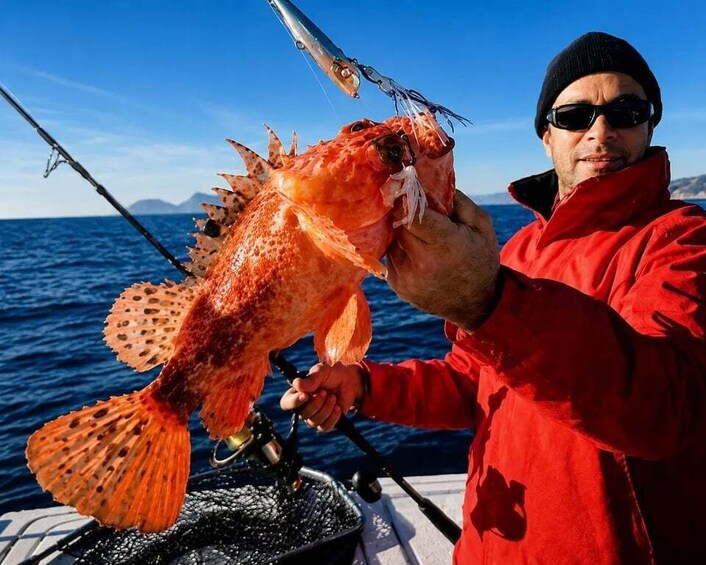 A person holding a large fish with a fishing rod in the background. 5