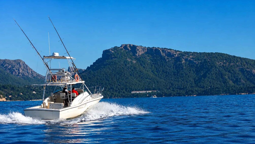 A speedboat on a calm sea with a mountainous backdrop. 1