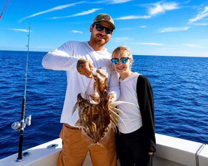 A person holding a large fish on a boat in the ocean. 3