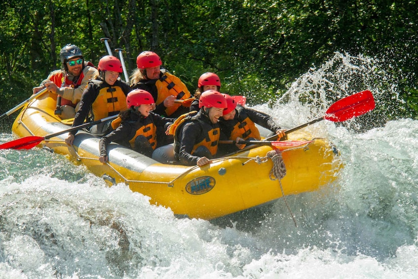 A group of people in a yellow inflatable raft navigating through white water rapids. 1