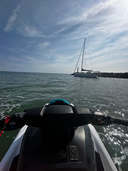 A boat's control panel and a sailboat in the distance on calm waters. 2
