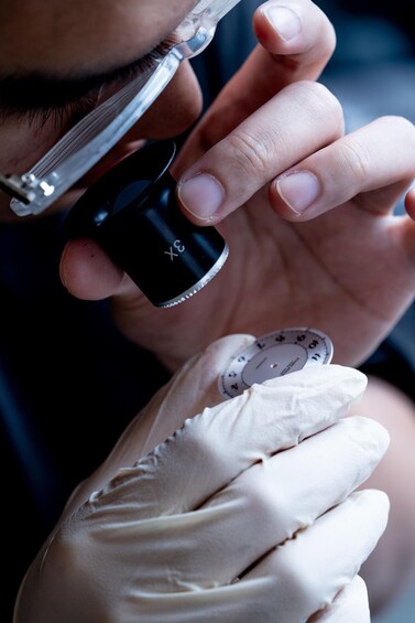 A person holding a magnifying glass near their eye, wearing a white glove. 2