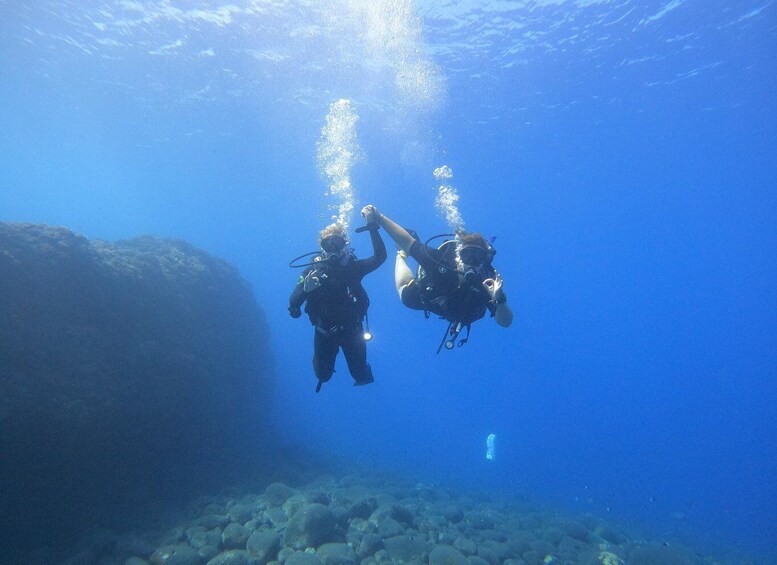 Two scuba divers underwater with bubbles rising to the surface. 1
