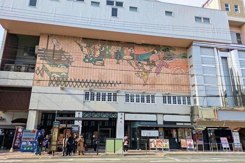 A building with a large mural, storefronts, and people walking on the sidewalk. 3
