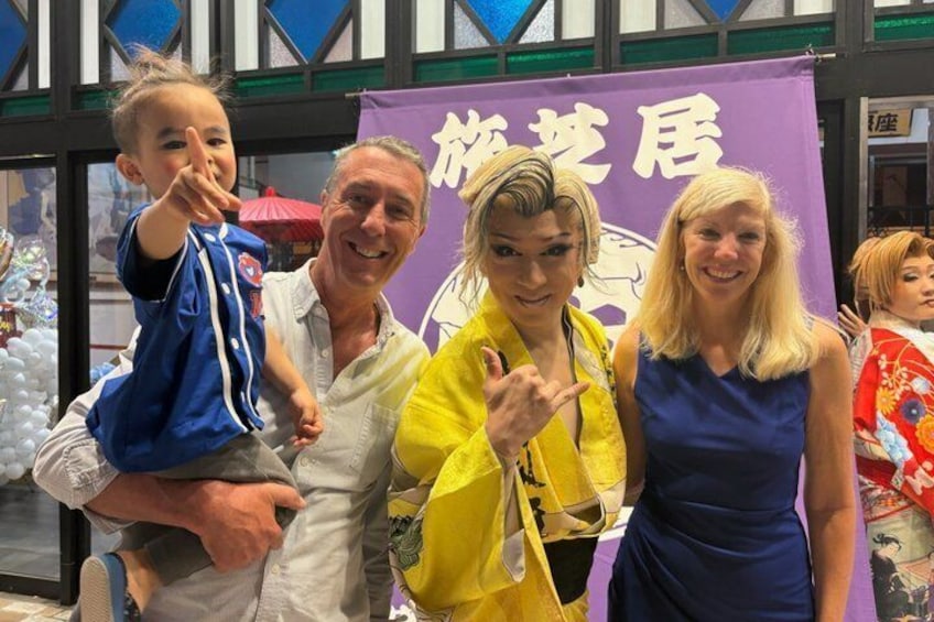 A group of people posing in front of a purple banner with Japanese characters. 5