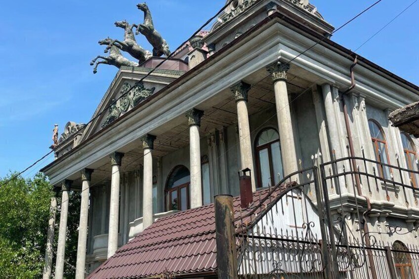 A classical building with columns, a red roof, and statues on the roof. 4