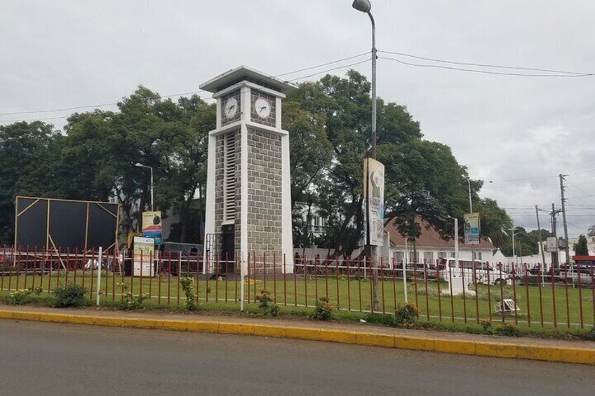 A clock tower, a fenced area, and a road with a yellow curb. 1