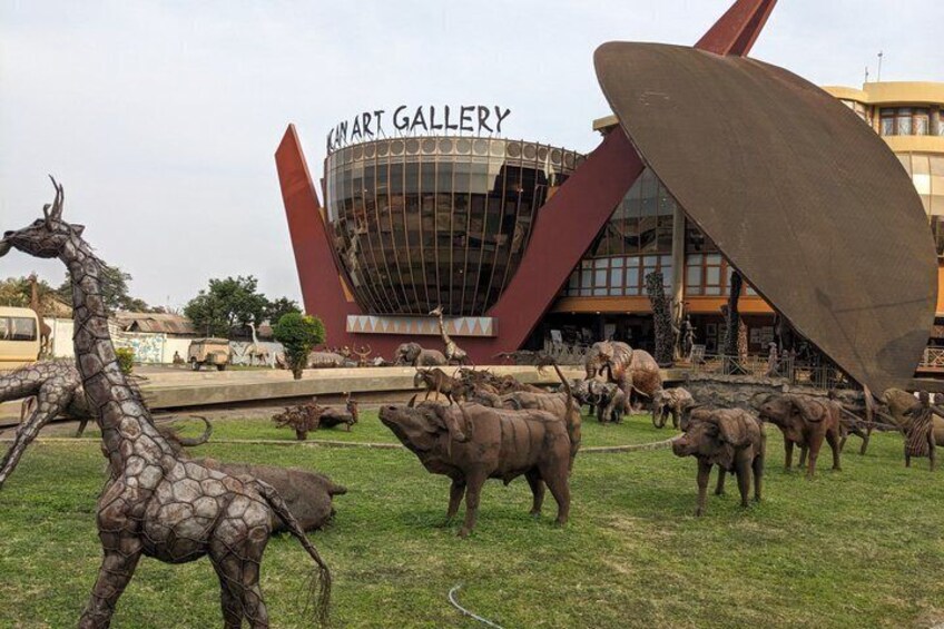 An art gallery with a unique red and brown structure, surrounded by various animal sculptures. 4
