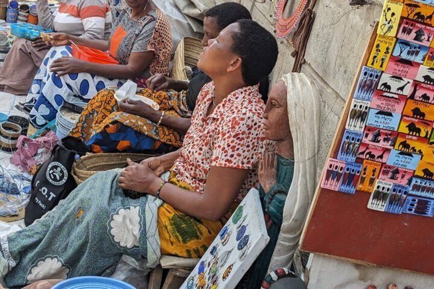 People sitting at a market stall with various goods and a display of wildlife posters. 5