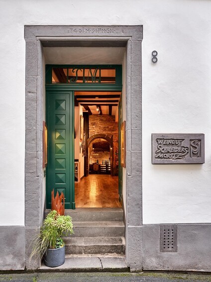 A building entrance with a green door, a staircase, and a sign reading 'WENG & SCHNEIDER MORITZ'. 2