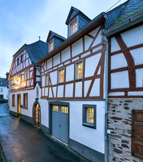 A traditional half-timbered building with a stone wall foundation, a wooden door, and a lit signboard. 1