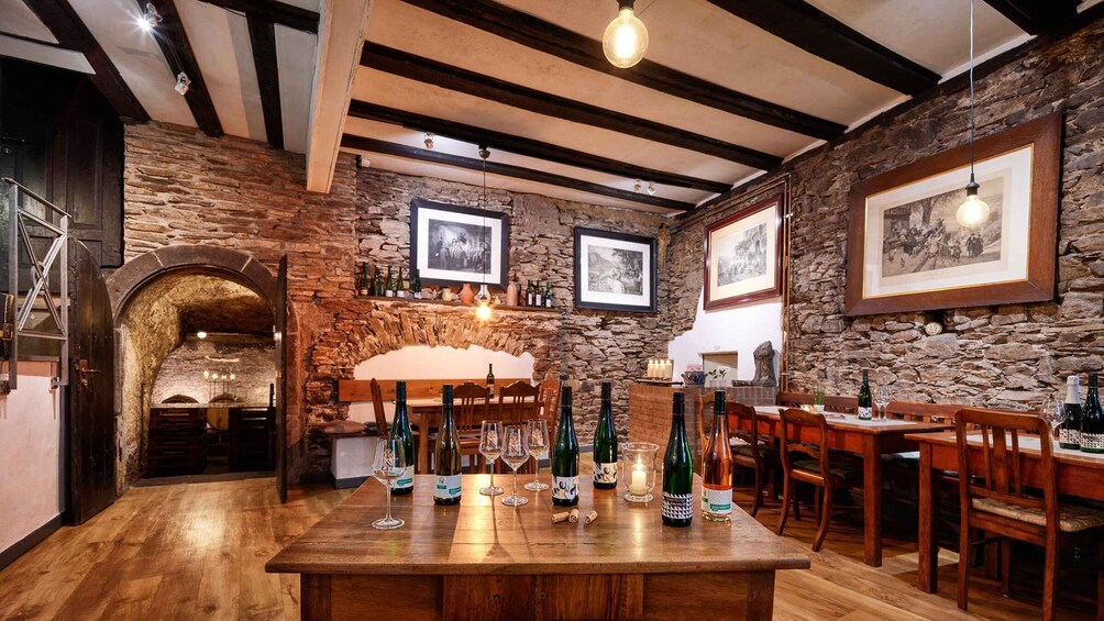 A rustic interior with exposed stone walls, wooden beams, and a bar area with bottles and glasses. 5
