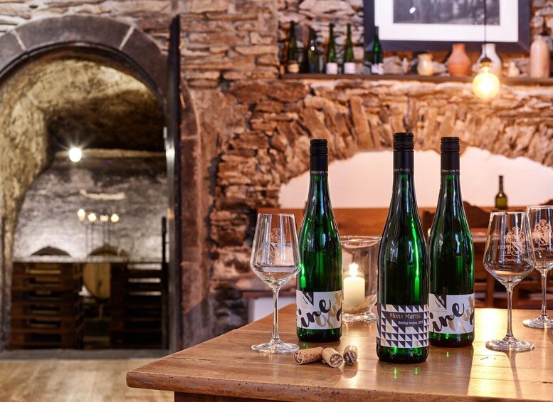 A rustic bar setting with three green wine bottles labeled 'Monsters Martini' and two empty wine glasses on a wooden table. 4