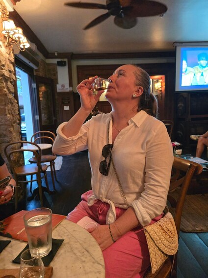 A person seated at a table in a restaurant, holding a glass. 3
