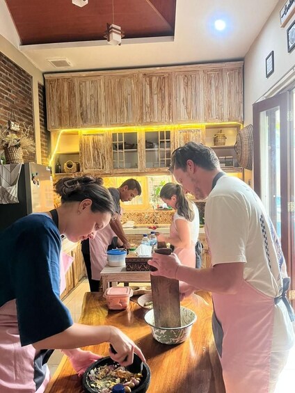 A group of people cooking in a kitchen with wooden cabinets and a brick wall. 2