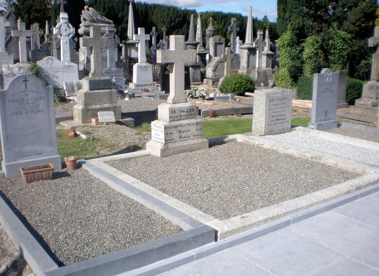 A cemetery with numerous gravestones, including crosses and headstones, surrounded by trees. 3