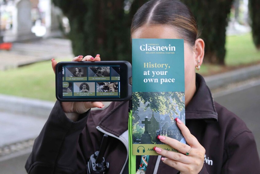 A person holding a smartphone displaying a photo gallery and a book titled 'Glasnevin: History, at your own pace.' 2