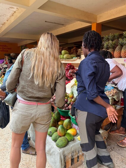 A market scene with people shopping for fruits like mangoes and pineapples. 2