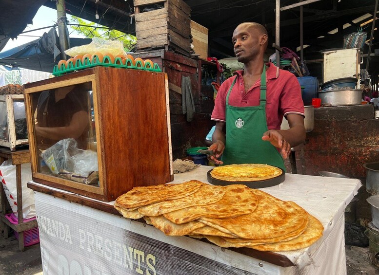 A street food vendor selling flatbreads, with a wooden display case and a sign reading 'WANDA PRESENTS.' 1
