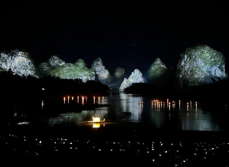 A nighttime scene with illuminated rock formations and a calm body of water reflecting the lights. 2