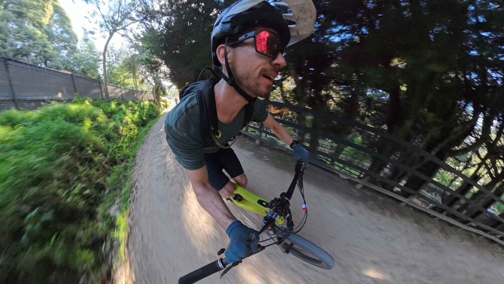 A person riding a mountain bike on a dirt trail surrounded by trees. 1