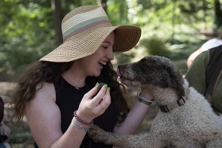 A person wearing a straw hat holding a curly-haired dog. 1