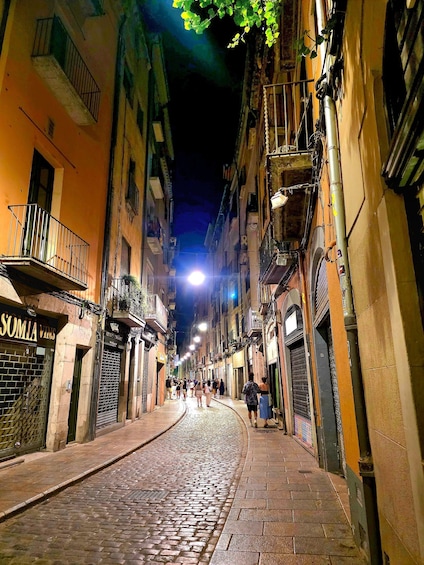 A cobblestone street at night with illuminated buildings and a few pedestrians. 3