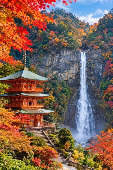 A traditional Japanese pagoda with a waterfall in the background. 2