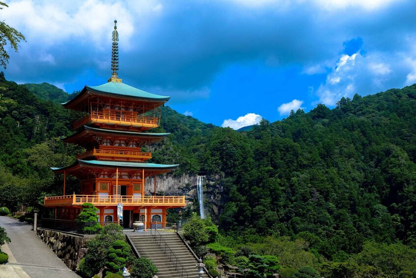 A multi-tiered pagoda with a traditional roof, surrounded by lush greenery and a waterfall. 1