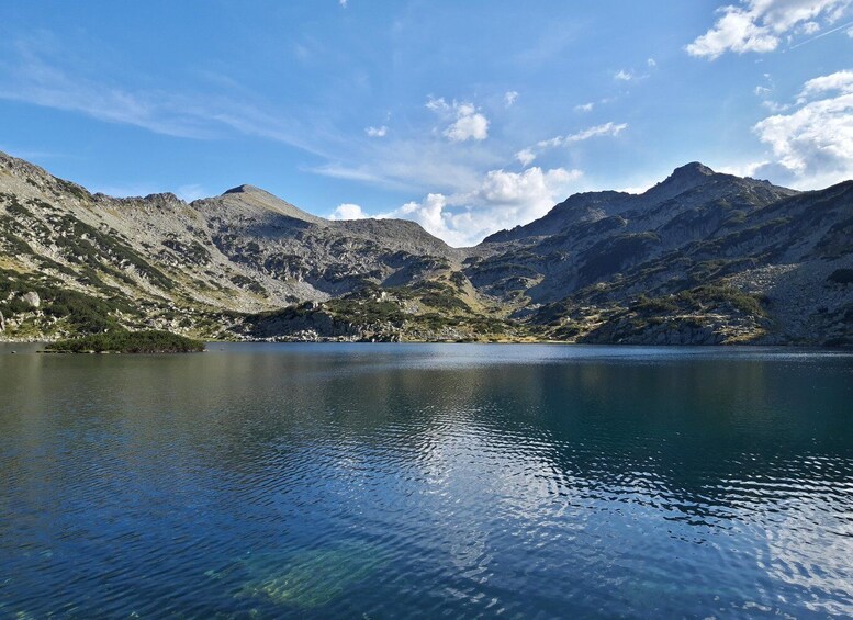 A tranquil lake surrounded by rugged mountains under a clear sky. 1