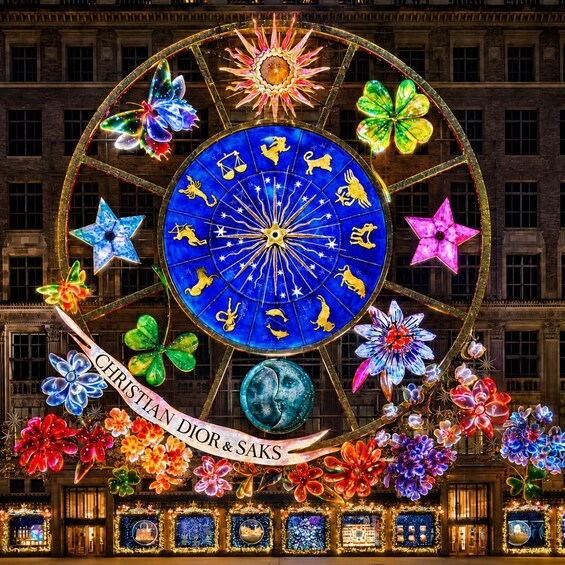 A large, illuminated zodiac wheel with floral decorations and a banner reading 'CHRISTIAN DIOR & SAKS' in front of a building. 4