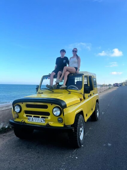 A yellow vehicle parked by the roadside with a coastal view in the background. 5